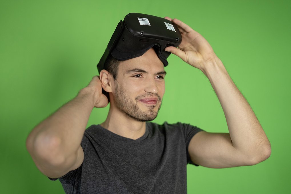 Man wearing VR glasses standing in front of a green background