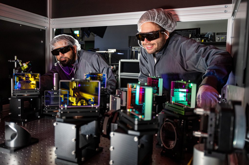 Two men in lab coats wearing safety goggles conducting experiments in a laboratory